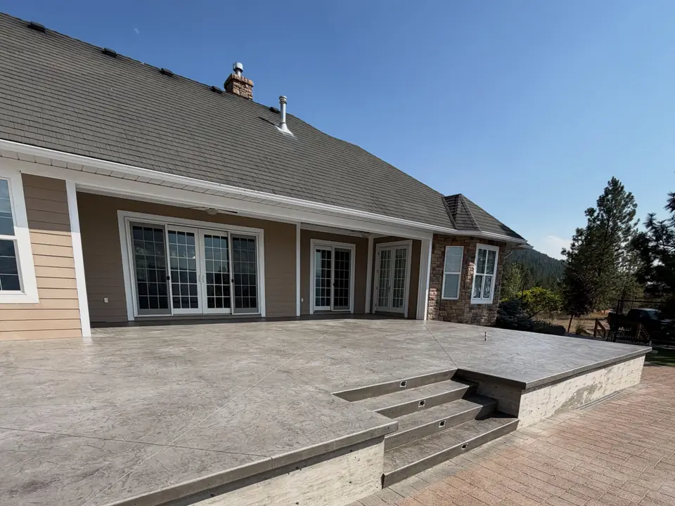Large concrete patio with built-in steps behind a home