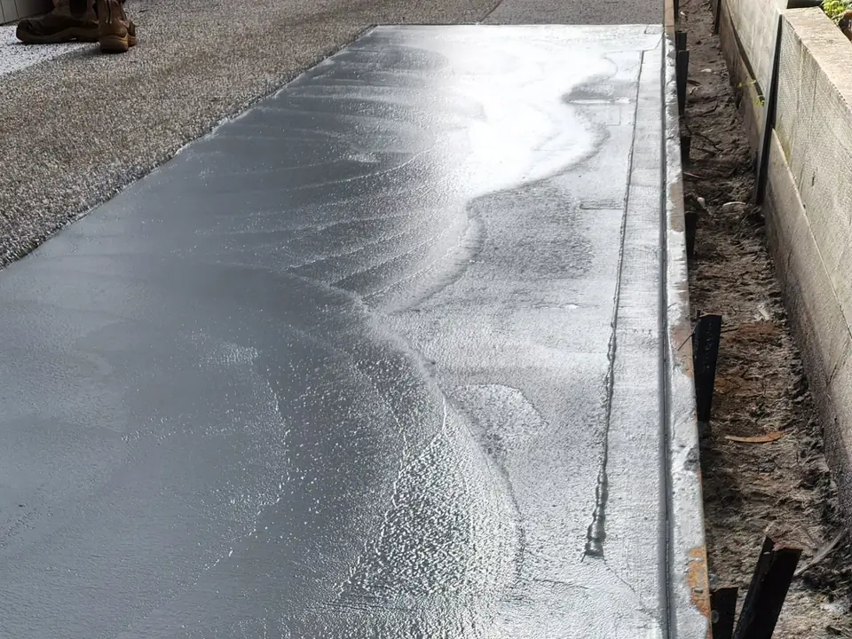 Freshly placed concrete section along a block wall