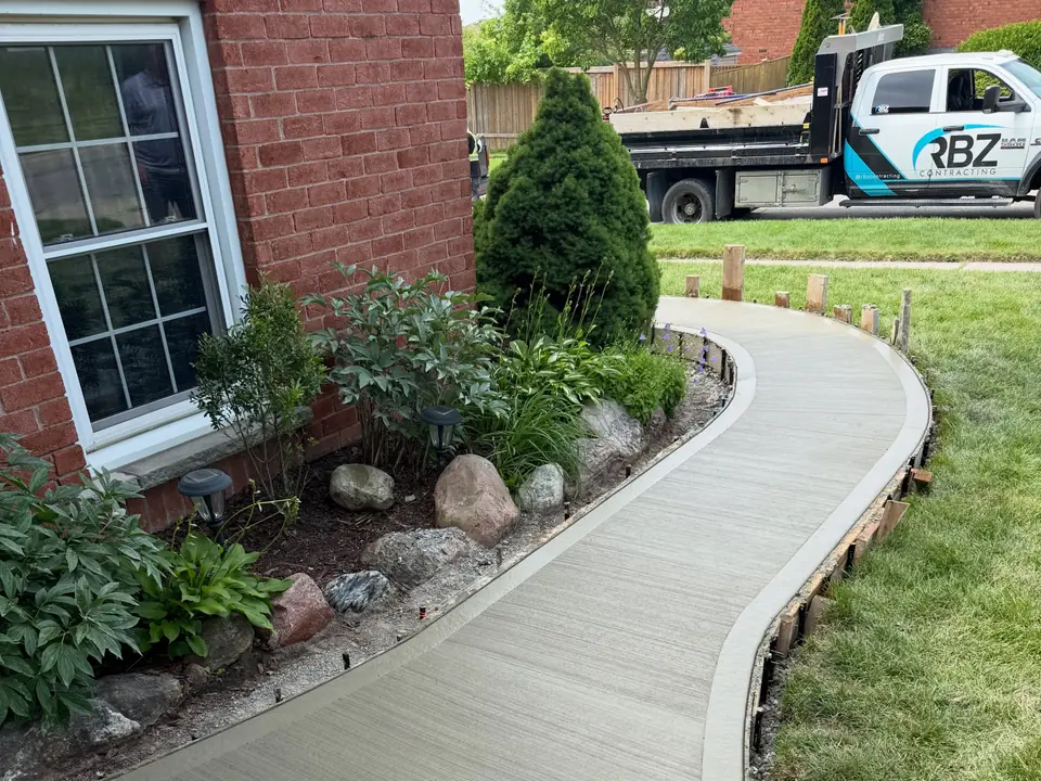 Curved concrete front walkway along a planting bed