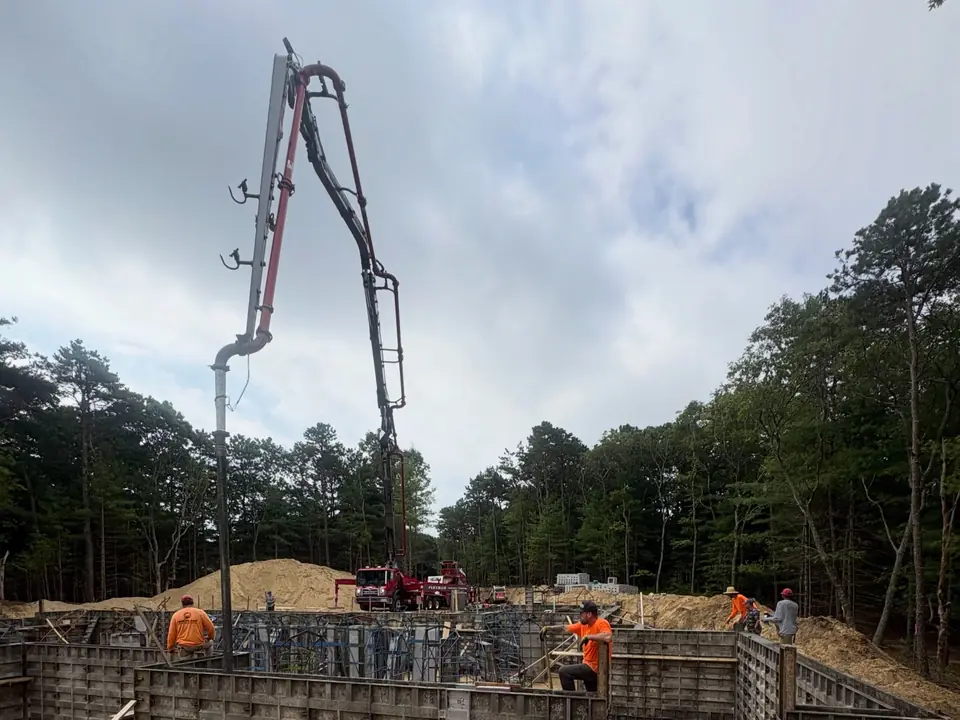 Concrete pump and crew pouring formed foundation walls
