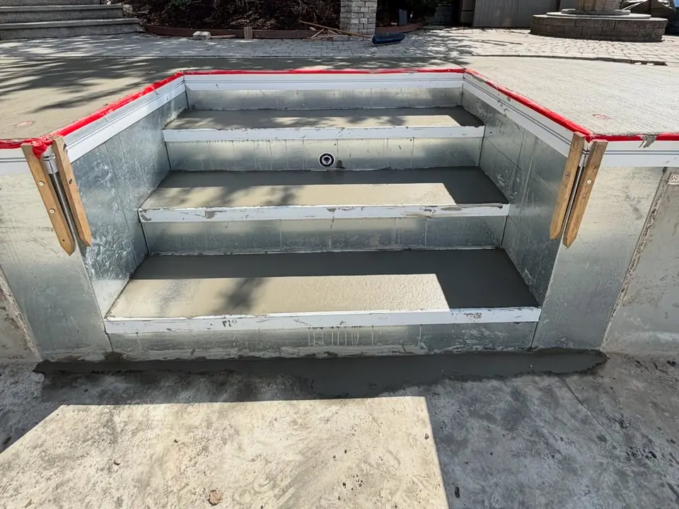 Broom-finished concrete deck and steps around a pool under construction, photo 1 of 10