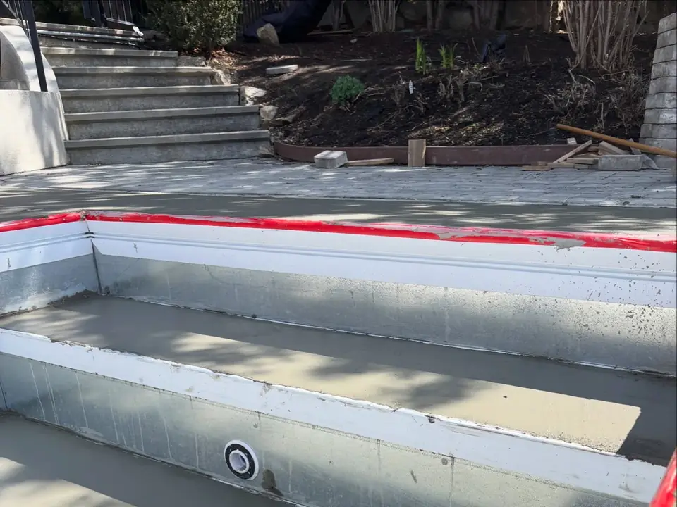 Broom-finished concrete deck and steps around a pool under construction, photo 9 of 10