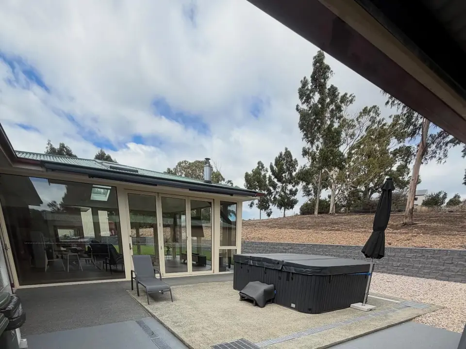 Concrete patio slab with a hot tub beside a sunroom
