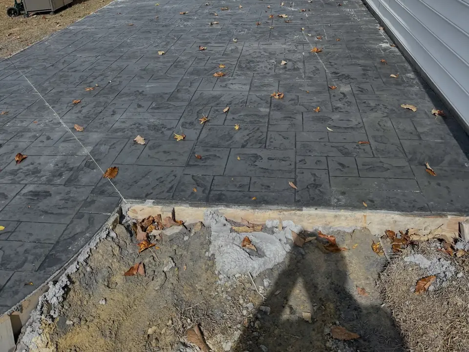 Gray stamped concrete with a stone pattern beside a house